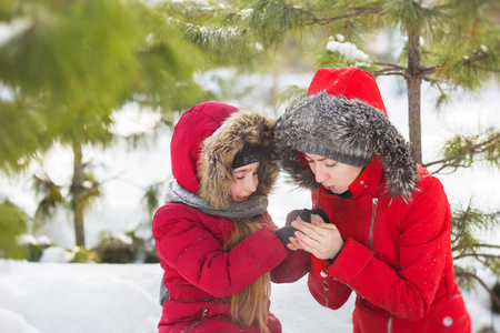 母亲温暖的雪在公园的小女儿的手