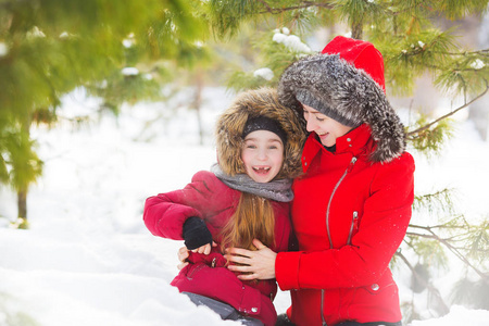 母亲的肖像和小女儿微笑在冬季木材中的雪