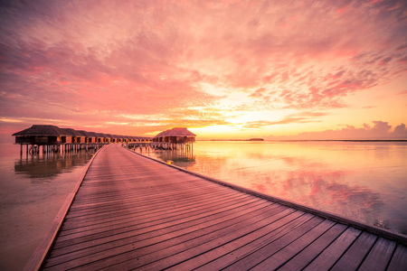 夏季旅游度假日落马尔代夫岛上的，豪华水别墅度假村。美丽的天空和云