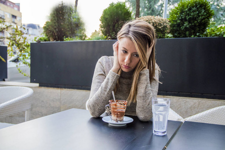郁闷的少女坐在咖啡店里的肖像.在咖啡厅的抑郁症的妇女.