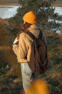 希普斯特年轻女孩与背包享受日落在雾蒙蒙的山顶上。背景图模型上的旅游旅行者。徒步旅行者在旅途中看阳光