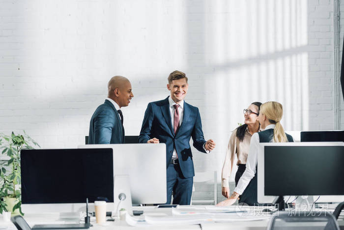 微笑的年轻多民族商人在开放空间办公室交谈