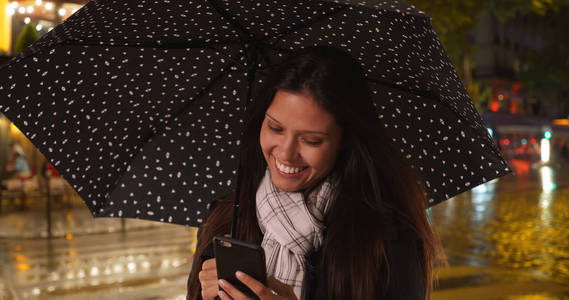 千禧年白种人妇女在夜间使用智能手机在暴雨