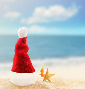 热带海滩白色沙滩上的圣诞老人帽。圣诞节或新年假期的概念