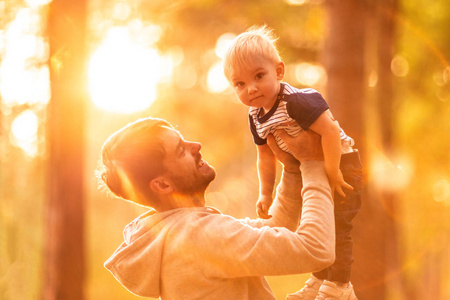 快乐的爸爸在户外玩耍时把孩子扔了照片