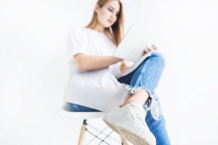一个年轻的时尚金发女孩的肖像, 穿着白色 t恤和蓝色牛仔裤使用平板电脑在白色背景