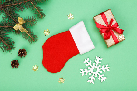 圣诞装饰。圣诞老人的靴子, 礼品盒, 冷杉树枝与锥和装饰雪花在绿色的背景。顶部视图。圣诞贺卡概念