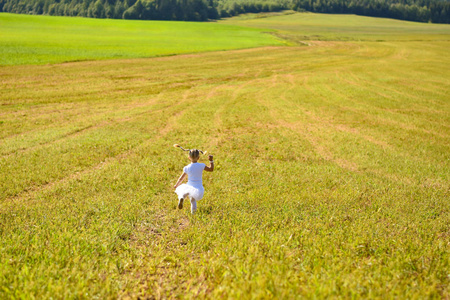 小女孩在白色礼服在下午奔跑领域