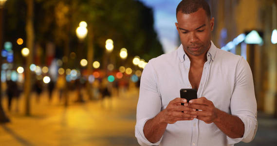 漂亮的民族男性用手机阅读香榭丽舍大街上的短信