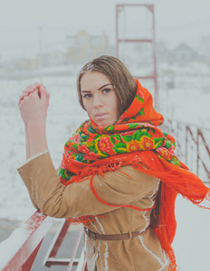 一条围巾在冬天里漂亮的女孩站在桥抓着栏杆