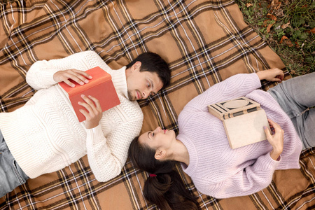 情侣在爱坐在秋天的公园和阅读书籍