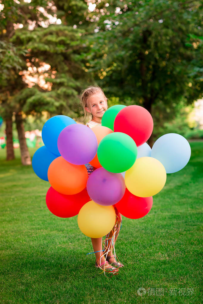 愉快的小女孩玩与大堆氦填充五颜六色的气球在公园
