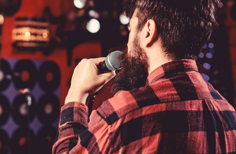 他喜欢在黑暗的卡拉 ok 大厅唱歌.人在格子衬衣举行话筒, 唱歌歌照片