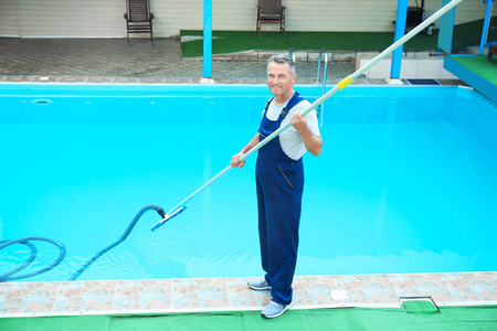 男性工人清洁室外游泳池与水下真空