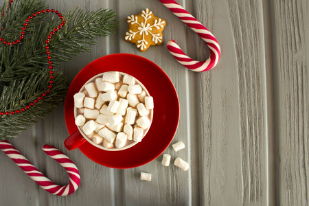 热可可与棉花糖在红色杯子和圣诞节构成在灰色木制的背景。顶部视图。复制空间