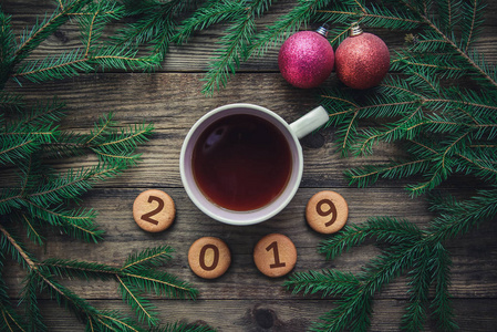 在2019年的新年上, 在木制背景下的饼干冷杉树枝玩具和一杯热茶上, 都有圣诞图片