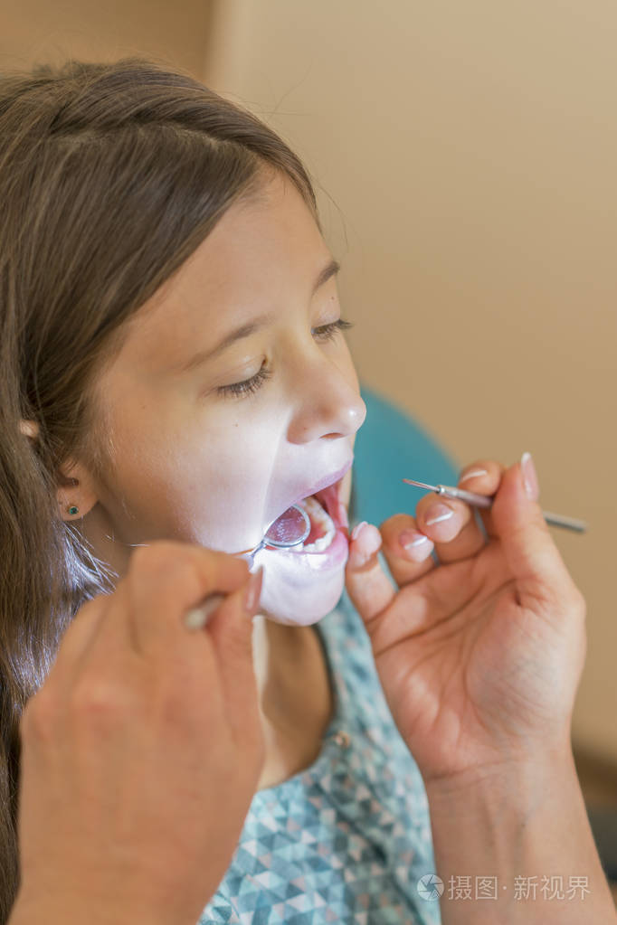 在牙科治疗后, 小女孩坐在牙医旁边的椅子上.