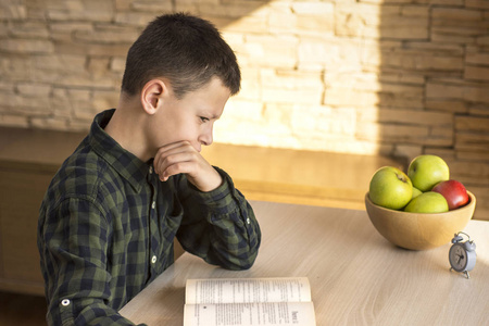 小男孩在家里思考一本书在桌子上照片