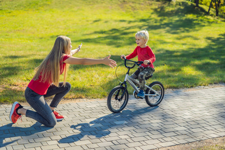 教儿子在公园骑自行车的年轻母亲