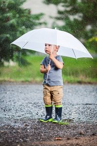 在暴雨中抱着雨伞的可爱孩子图片