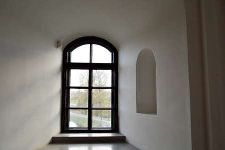 一个狭窄的小窗户, 在一座古老的古石上有一个框架, 在一座古老的城堡里, 白色的厚厚的水泥墙。背景介绍