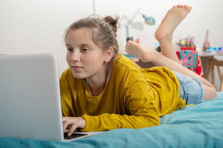 十几岁的女孩躺在床上, 用笔记本电脑