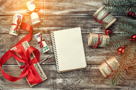旧木的圣诞节背景。用美国和欧洲的钱的圣诞树。节日礼物。顶部视图。带有笔记本的文本的空间。光效