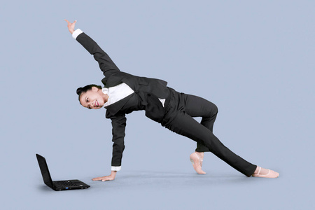 亚洲女商人穿着芭蕾鞋, 而与笔记本电脑跳舞在工作室照片