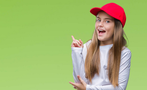年轻美丽的女孩戴着红色的帽子孤立的背景与一个灿烂的笑容在脸上, 用手和手指指着一边看着镜头
