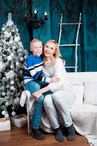 快乐的年轻母亲和她的儿子在家里与圣诞树和礼物