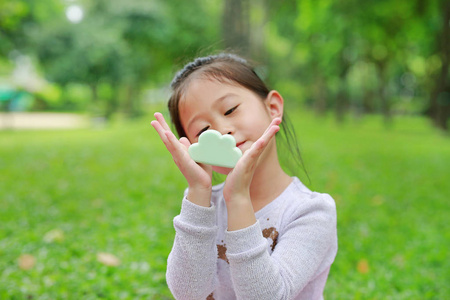 可爱的亚洲小女孩显示一些食物在她的手中在绿草花园