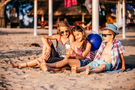 积极的孩子一起在沙滩上玩手机的肖像