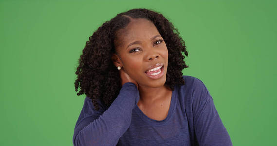 黑色女性与脖子疼痛摩擦脖子看在绿色屏幕上的相机