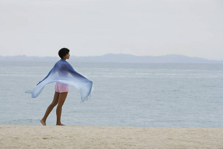 女人穿着蓝色的围巾，看着海洋
