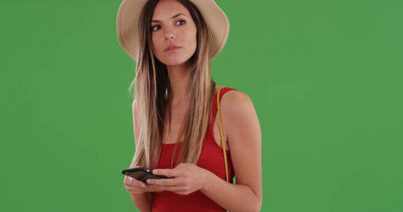 可爱的嬉皮士女性戴帽子使用智能手机在绿色屏幕上的文字