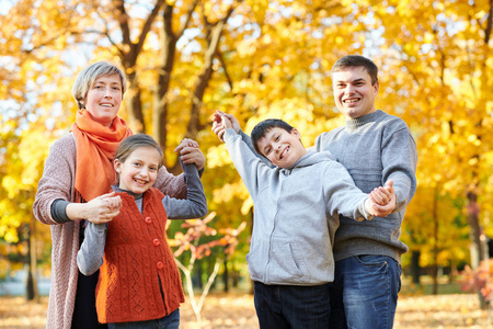 幸福的家庭在秋城公园散步。孩子们和家长摆姿势, 微笑, 玩耍和娱乐。明亮的黄色树