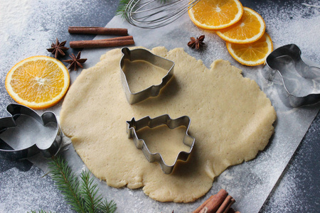 圣诞饼干。切姜饼。在家里烤饼干的过程。姜饼面团饼干, 饼干, 肉桂棒, 橘子和冷杉树枝。新年或寒假还活着, 背景。顶视图