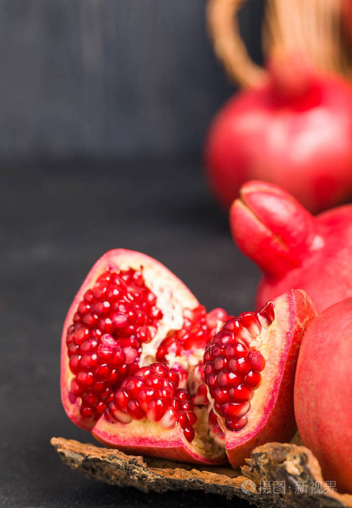 成熟的红色石榴在柳条篮和种子在勺子特写镜头在黑色背景下-季节性的