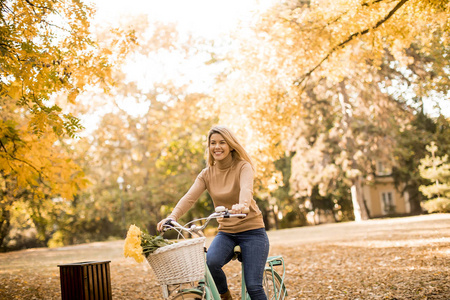 愉快的活跃妇女骑自行车在金秋公园