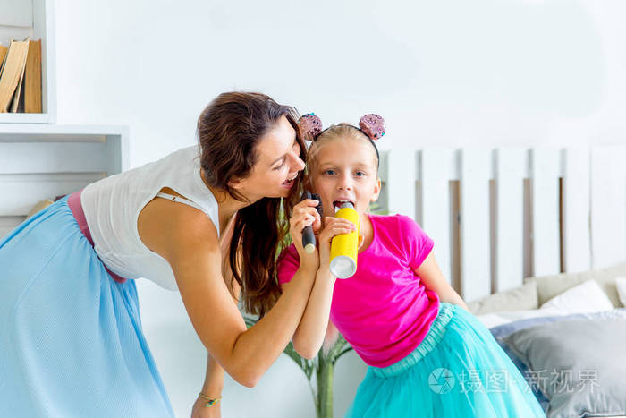 母亲和她的小女儿一起对着麦克风唱歌