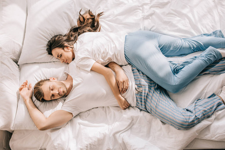 美丽的年轻夫妇穿着睡衣睡在床上的最高视图在早晨照片