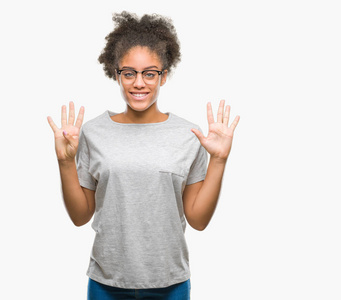 年轻的美国黑人妇女戴着眼镜在孤立的背景显示和指向九的手指, 而微笑着自信和快乐