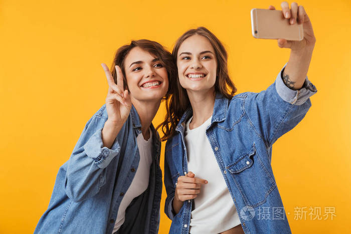 图像的情感年轻女性朋友查出的黄色墙壁背景自拍手机