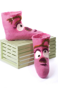 在木箱上的白色背景上有图案的粉红色毛毡袜子