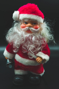 假日壁纸背景的圣诞老人玩具与银色响铃在他的手隔绝在黑色背景