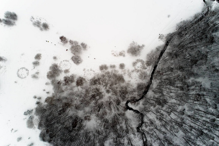 这条河在冬天流经一个公园, 树上躺着积雪。空中摄影