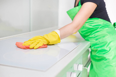 特写镜头的女性手在橡胶黄色手套清洁在家里的厨房炊具面板。家, 家政的概念。清洁服务