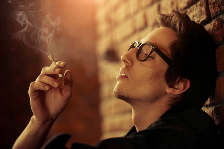好看的香烟有魅力的年轻男子若有所思地和冷静地抽一支烟.