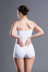背痛，肾脏炎症 疼痛在女人的身体在灰色的背景上