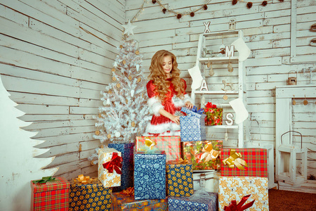 快乐的女孩打开礼物盒隔离房间圣诞装饰。冬季假期概念